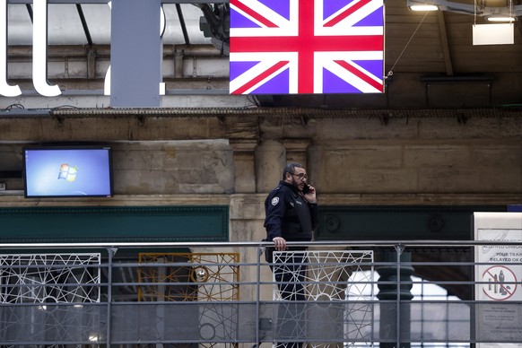 epa11049243 A French Customs Police officer stands near a Union Jack flag at Gare du Nord railway station in Paris, France, 30 December 2023. Flooding in southern England has caused numerous cancellat ...