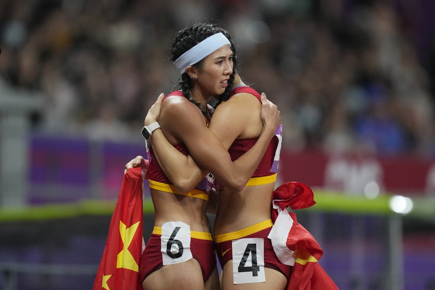 Gold medalist China's Lin Yuwei, left, hugs compatriot and silver medalist China's Wu Yanni after their women's 100-meter hurdles final at the 19th Asian Games in Hangzhou, China, Sunda ...
