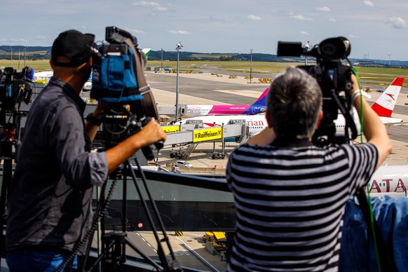 epa09395206 Journalists film the Austrian Airlines flight 0S52, with Belarusian athlete Krystsina Tsimanouskaya on board, at a gate at Vienna International Airport (VIC) in Schwechat, Austria, 04 Augu ...