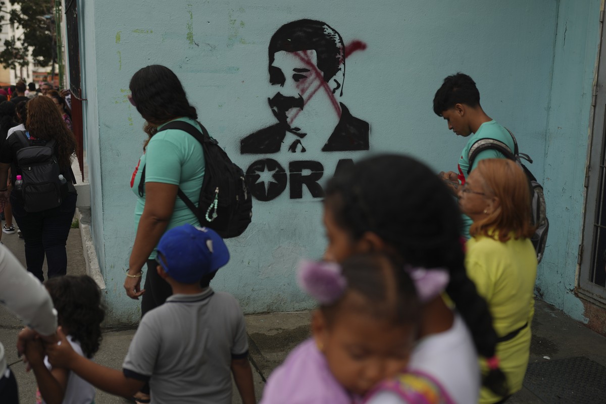 People walk past a mural of President Nicolas Maduro with an X drawn over his face in Caracas, Venezuela, Monday, Jan 6, 2025, days ahead of his inauguration. (AP Photo/Ariana Cubillos)