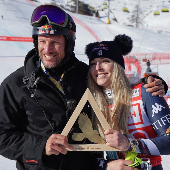 United States&#039; Lindsey Vonn poses with the trophy with Aksel Lund Svindal, left, after winning an alpine ski, women&#039;s World Cup downhill, in St. Moritz, Switzerland, Friday Dec. 12, 2025. (A ...
