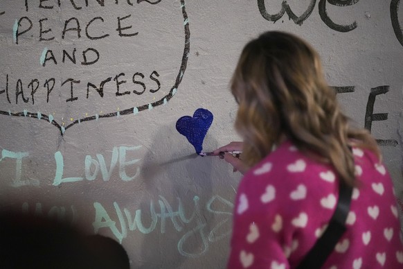 A woman paints a heart at a memorial for the victims of a deadly truck attack on New Year&#039;s Day in New Orleans, Friday, Jan. 3, 2025. (AP Photo/Gerald Herbert)