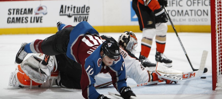 Colorado Avalanche right wing Sven Andrighetto, front, dives over Anaheim Ducks goaltender John Gibson after scoring a goal during the third period of an NHL hockey game Friday, March 15, 2019, in Den ...