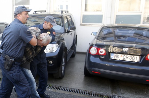 FILE - In this Sunday Oct. 16, 2016 file photo, Montenegrin police officers escort a man suspected of planning armed attacks after the parliamentary vote in Podgorica, Montenegro. A court in Montenegr ...