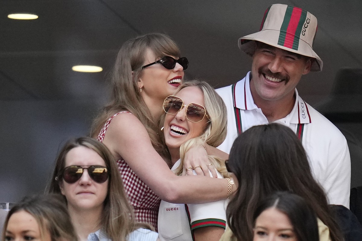Taylor swift, left, hugs Brittany Mahomes as Travis Kelce looks on during the men's singles final between Jannik Sinner, of Italy, and Taylor Fritz, of the United States, at the U.S. Open tennis  ...