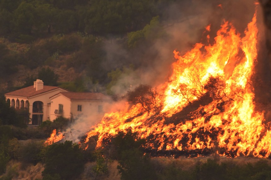 In this Thursday, Dec. 14, 2017, photo provided by the Santa Barbara County Fire Department, flames from a back firing operation underway rise behind a home off Ladera Lane near Bella Vista Drive in S ...