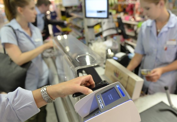 Eine Frau bezahlt mit dem Smartphone an der Kasse einer Coop Filiale in Zuerich am Dienstag, 1. Juli 2014. Mit &quot;Tapit&quot; kommt erstmals eine Smartphone App auf den Schweizer Markt, die das Bez ...