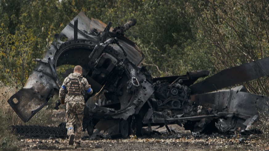 A Ukrainian soldier passes by a Russian tank damaged in a battle in a just freed territory on the road to Balakleya in the Kharkiv region, Ukraine, Sunday, Sept. 11, 2022. (AP Photo)