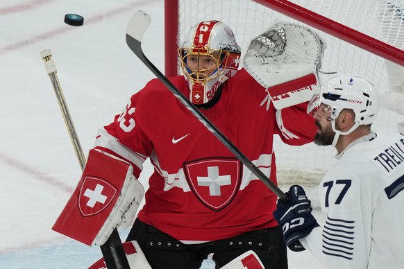France's Sacha Treille, right, tries to tip the puck past Switzerland's goalkeeper Leonardo Genoni during a preliminary round match of men's ice hockey between Switzerland and France at ...