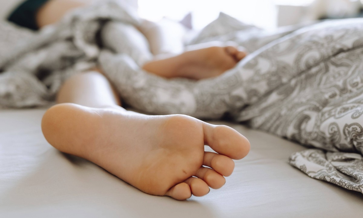 Schlafende junge Frau liegt mit nackten Füssen.