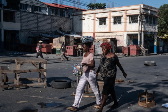epa11256087 Two women walk near the Champs de Mars, the main public square in Port-au-Prince, Haiti, on 02 April 2024, a day after a failed attack by gangs near the National Palace, in Port-au-Prince, ...
