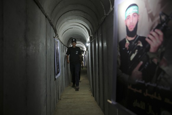 A Palestinian youth walks inside a tunnel used for military exercises during a weapon exhibition at a Hamas-run youth summer camp, in Gaza City, Wednesday, July 20, 2016. The photo at right shows a Ha ...