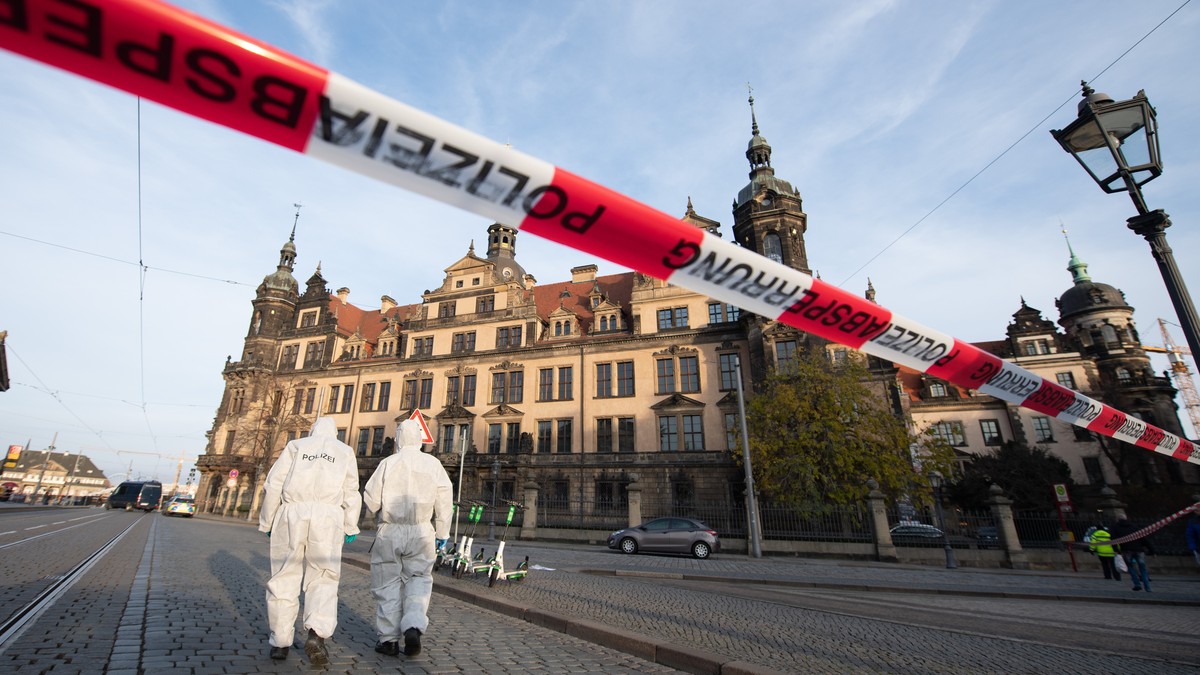 25.11.2019, Sachsen, Dresden: Zwei Mitarbeiter der Spurensicherung stehen vor dem Residenzschloss mit dem Grünen Gewölbe hinter einem Absperrband. In Dresdens Schatzkammer Grünes Gewölbe ist am frühen ...