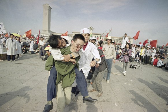 FILE - In this May 16, 1989 file photo, medics rush a Beijing university student from Tiananmen Square after he collapsed on the third day of a hunger strike in Beijing. A quarter century after the Co ...