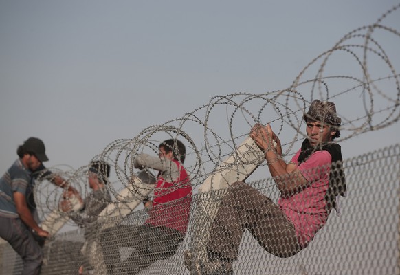 Syrische Flüchtlinge überwinden den Grenzzaun zur Türkei (14.07.2015).