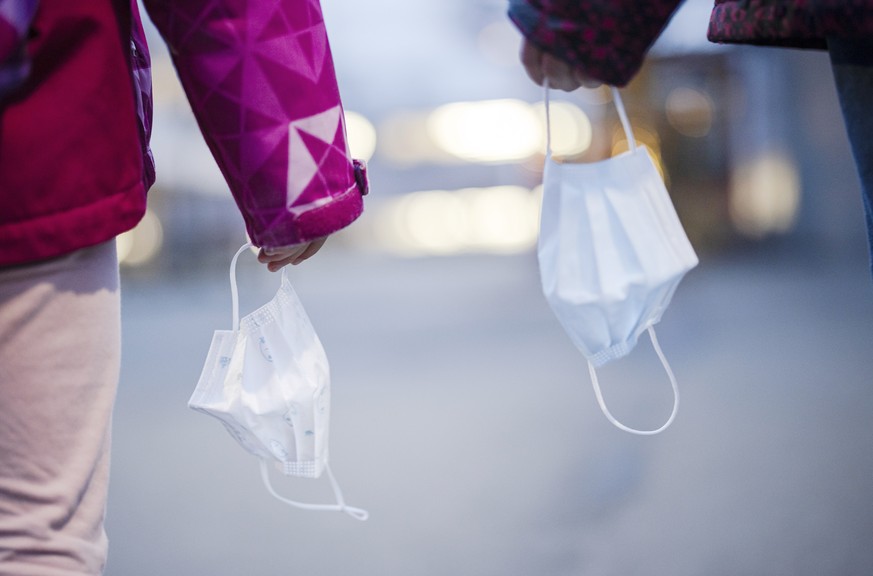 Primarschuelerinnen halten Kinder Masken auf einem Pausenplatz einer Schule, aufgenommen am Montag, 3. Januar 2022 in Zuerich. Die Maskentragpflicht im Kanton Zuerich wird mit dem Schulstart nach den  ...