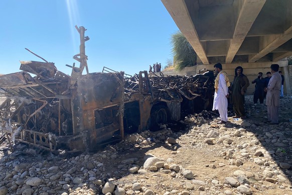 People look at the burnt wreckage of a bus accident in Bela, an area of Lasbela district of Balochistan province, Pakistan, Sunday, Jan. 29, 2023. The passenger bus crashed into a pillar and fell off  ...