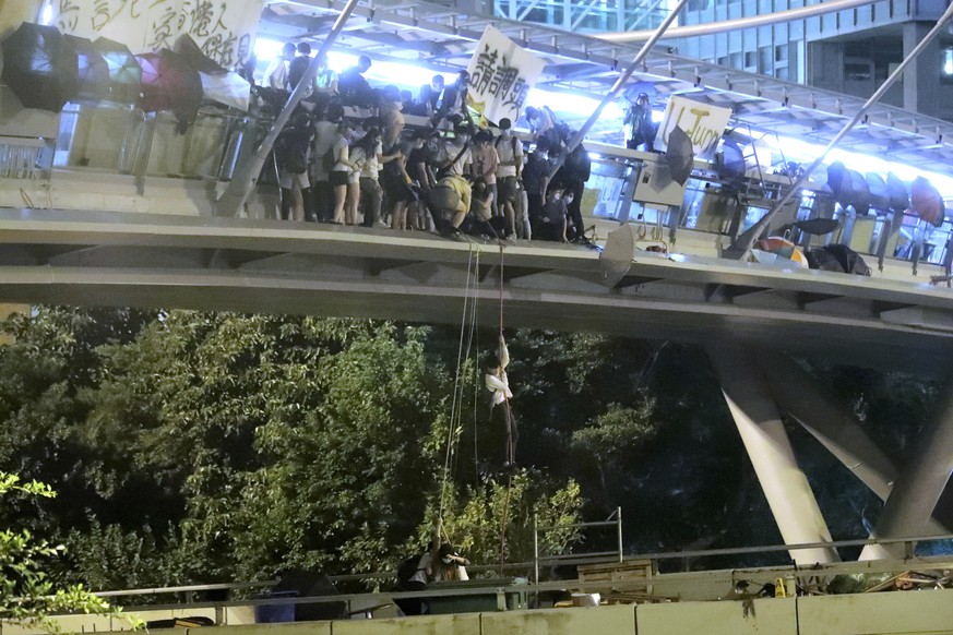 Protestors use a rope to lower themselves from a pedestrian bridge to waiting motorbikes in order to escape from Hong Kong Polytechnic University and the police in Hong Kong, Monday, Nov. 18, 2019. As ...
