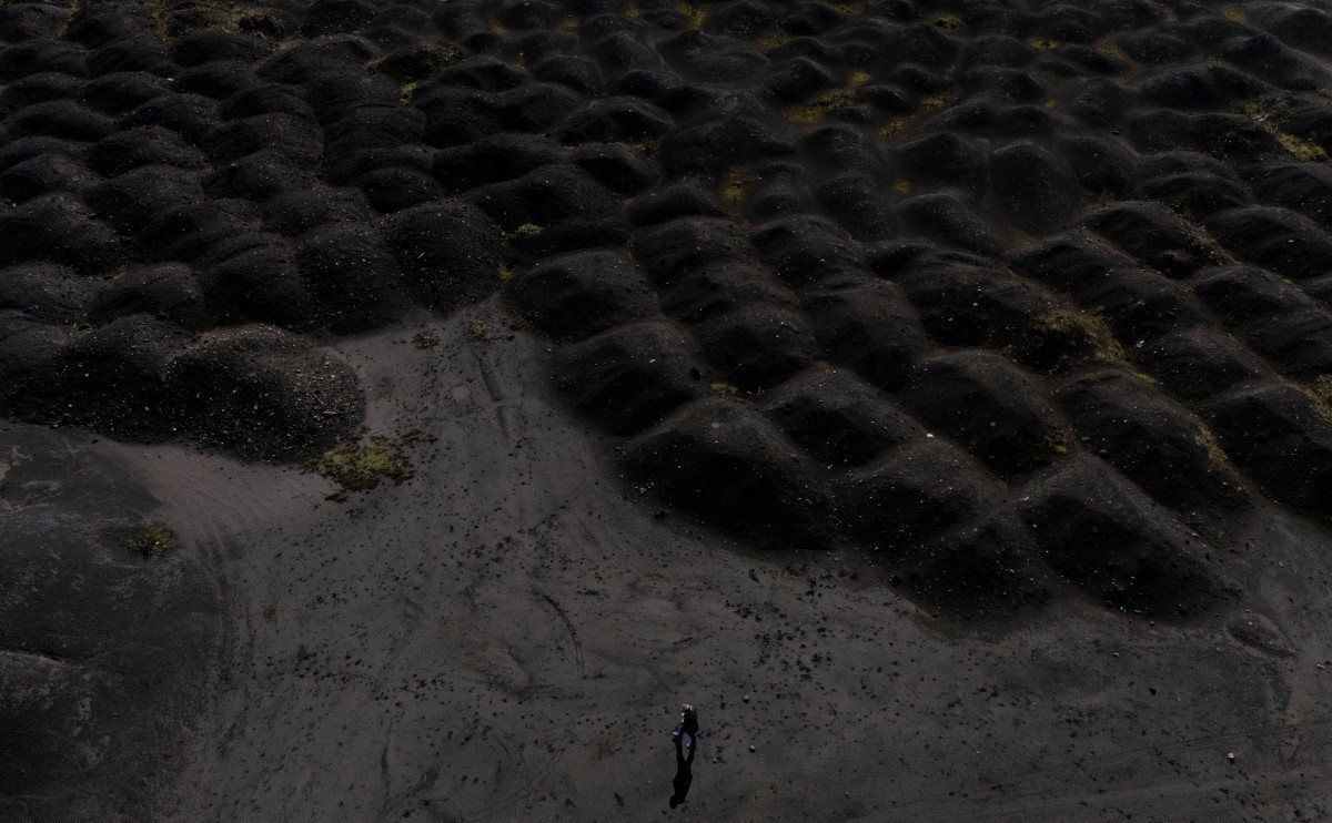 (FILES) This aerial photo shows a man walking near waste dumps of the metallurgical plant in Elbasan, on March 7, 2025. For several days this summer the Albanian city of Elbasan choked in a dense clou ...