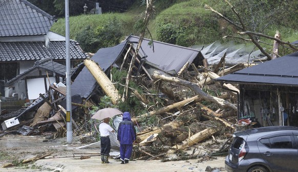 People stand by a mudslide site following a storm in Ayabe, Kyoto prefecture, western Japan Tuesday, Aug. 15, 2023. A strong tropical storm lashed central and western Japan with heavy rain and high wi ...