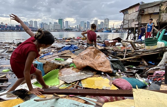 epa10894923 Villagers gather belongings after a storm surge caused by an approaching typhoon destroyed their homes, in a coastal village in Manila, Philippines, October 2, 2023. The Philipp...