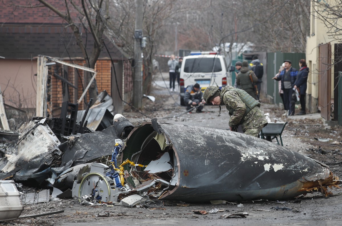 epa09783630 A soldier looks at the debris of a military plane that was shot down overnight in Kiev, Ukraine, 25 February 2022. Russian troops entered Ukraine on 24 February prompting the country' ...