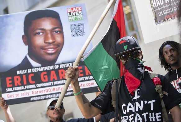 epa07719376 A man covers his face during a Black Lives Matter of Greater New York protest at the US Department of Justice building in support of an indictment for the death of Eric Garner in Washingto ...