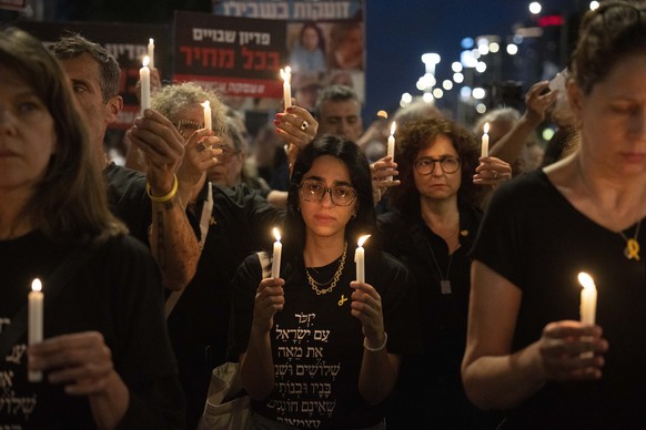 Family, friends and supporters of hostages held in the Gaza Strip by the Hamas militant group holds candles and stand still to observe one minute of silence as air raid sirens sound to mark Israel&#03 ...
