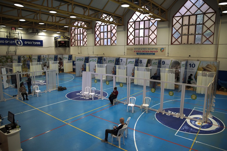 Israelis wait to receive coronavirus vaccine at a COVID-19 vaccination center, set up on a basketball court in Hod Hasharon, near Tel Aviv, Israel, Wednesday Jan. 6, 2021. (AP Photo/Oded Balilty)