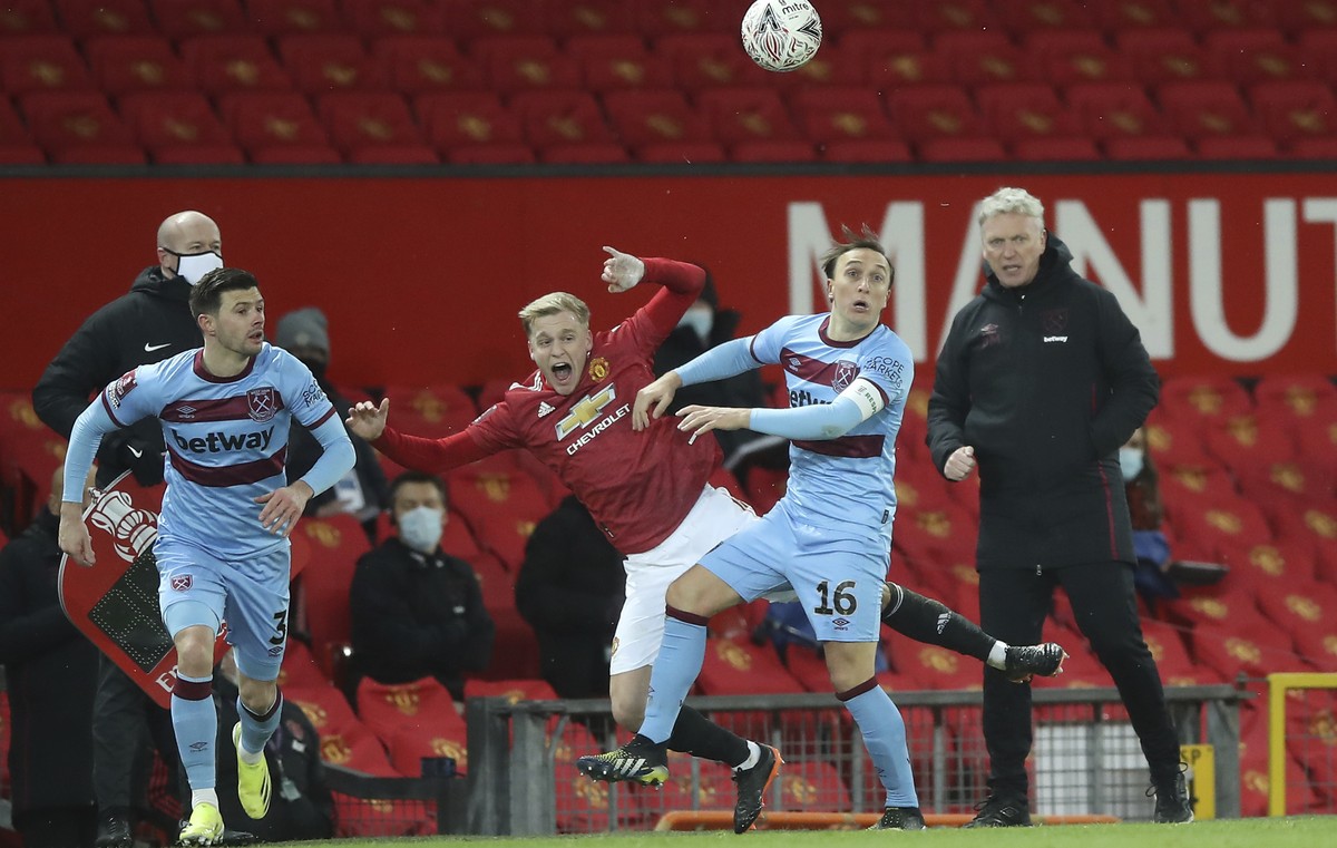 Manchester United's Donny van der Beek, left, challenges for the ball with West Ham's Mark Noble as West Ham's manager David Moyes watches during the English FA Cup 5th round soccer mat ...