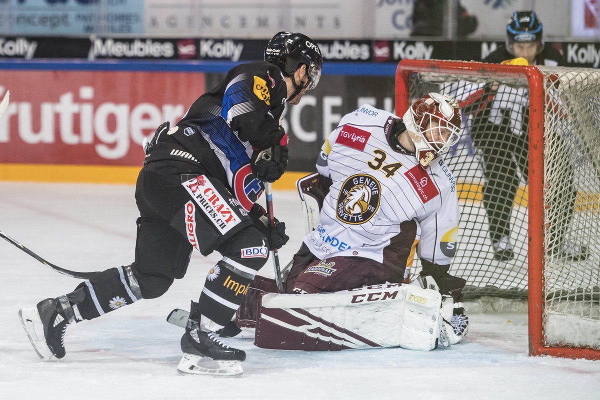 L'attaquant fribourgeois Jim Slater, gauche, marque un but au gardien genevois Gauthier Descloux, droite, lors de la rencontre du championnat suisse de hockey sur glace de National League entre l ...