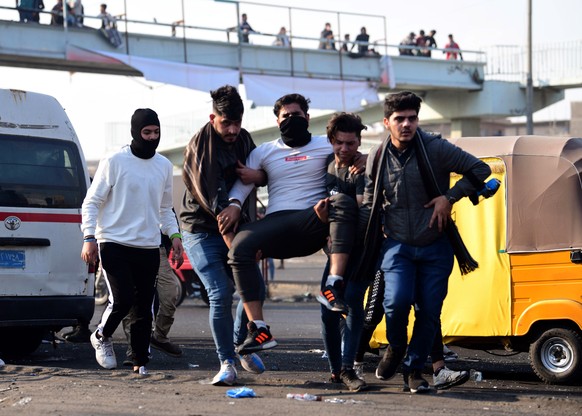 epa08145366 Iraqi protesters help a person affected by tear gas, which was dispensed by riot police during clashes following a protest at the Al-Tayaran square in central Baghdad, Iraq, 20 January 202 ...