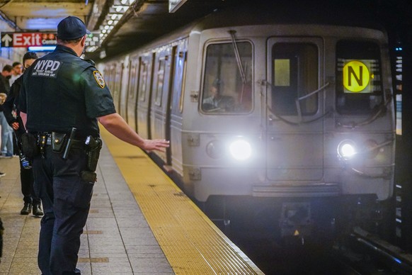 FILE - As a subway train enters the Canal St. Q and N station, a NYPD transit officer from the anti terrorism unit gestures to the driver, Tuesday, May 24, 2022, in New York. In the aftermath of a mas ...