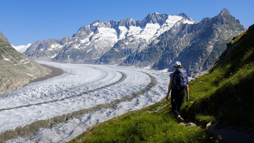A woman walks next to the Swiss Aletsch Glacier during a beautiful summer day above Bettmeralp in Wallis, Switzerland, this Sunday, July 8, 2018. The Swiss Aletsch glacier, one of the largest ice stre ...