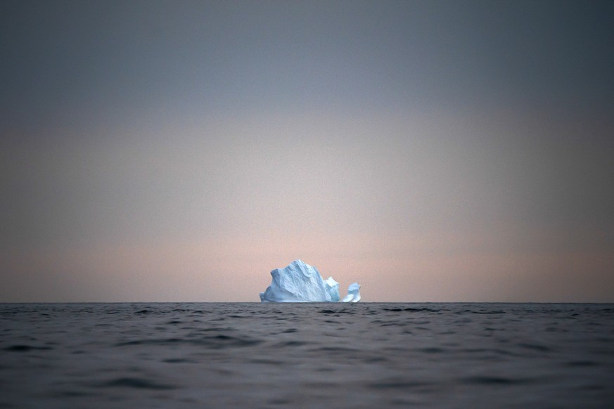 In this Aug. 15, 2019, photo, a large Iceberg floats away as the sun sets near Kulusuk, Greenland. Greenland is where Earth&#039;s refrigerator door is left open, where glaciers dwindle and seas begin ...