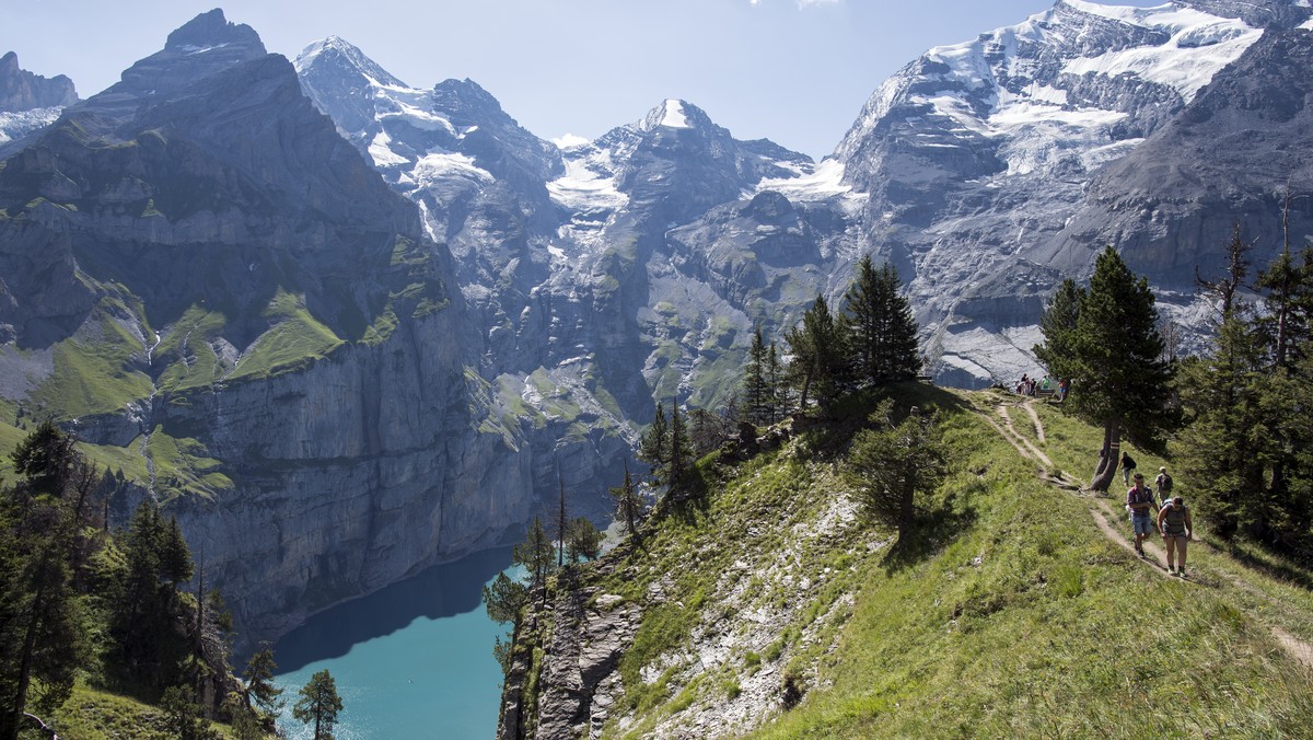 People walk around the lake of Oeschinen "Oeschinensee" (1578 meters above sea) and the mountains, above Kandersteg, in the Bernese Oberland, this Sunday, July 30, 2017. (KEYSTONE/Anthony An ...