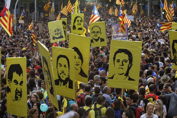 Protestors hold pictures of Catalan high-profile separatist politicians, some jailed and others who are fugitives from Spanish law after fleeing the country, during a demonstration in Barcelona, Spain ...