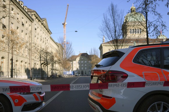 Police vehicles are parked in front of the Swiss Parliament, the Bundeshaus, during a large-scale operation of the Bern police, where several buildings were evacuated and the Bundesplatz and some stre ...