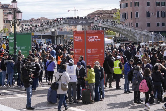 FILE - Stewards check tourists QR code access outside the main train station in Venice, Italy, Thursday, April 25, 2024. Venice on Sunday July 14, 2024 wraps up a pilot program charging day-trippers a ...