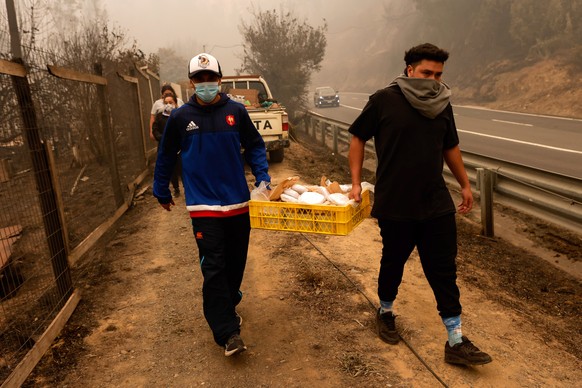 epa10449880 Residents share food during efforts to recover belongings after a fire, in Santa Juana, Chile, 05 February 2023. More than 800 people have been left homeless in Chile due to forest fires t ...