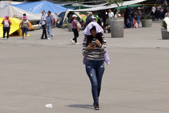 A woman walking covering herself from the sun with a jacket because to the high temperatures that have been registered in the last few days. In the coming days the third heat wave will hit Mexico, it  ...