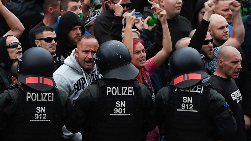 epa06977356 Right wing protesters gesture towards police in riot gear as they gather at the place where a man was stabbed in the night of the 25 August 2018, in Chemnitz, Germany, 27 August 2018. A 35 ...