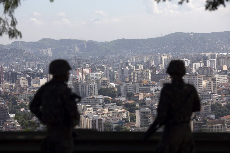 Soldiers on patrol are silhouetted against the skyline of the Lins Complex of slums in Rio de Janeiro, Brazil, Tuesday, March 27, 2018. Thousands of troops and police are entering a complex of favelas ...