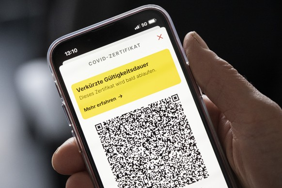 Eine Frau haelt ihr Mobiltelefon mit einer Meldung der Verkuerzten Gueltigkeitsdauer &quot;Dieses Zertifikat wird bald ablaufen&quot; in der Hand, aufgenommen am Donnerstag, 3. Februar 2022 in Zuerich ...