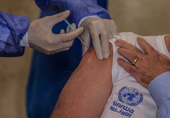 epa09033627 The director of United Nations Relief and Works Agency for Palestine Refugees (UNRWA) in Gaza Matthias Schmale (R) receives a shot of the Sputnik V Covid-19 vaccine at Al Sheikh Redwan cli ...