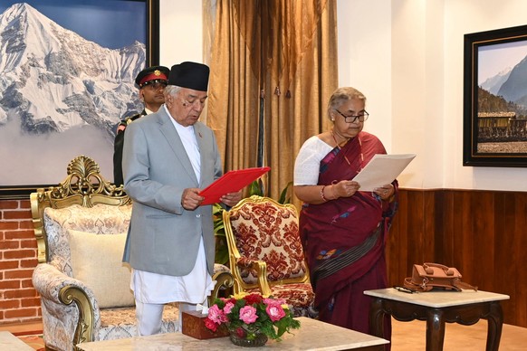 In this photo provided by the Nepalese President House, former Supreme Court Chief Justice Sushila Karki, right, is administered the oath of office by Nepalese President Ram Chandra Poudel, center, in ...