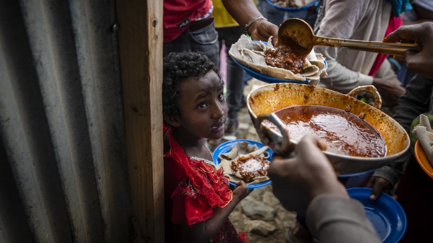 FILE - Elena, 7, center, lines up with other displaced Tigrayans to receive food donated by local residents at a reception center for the internally displaced in Mekele, in the Tigray region of northe ...