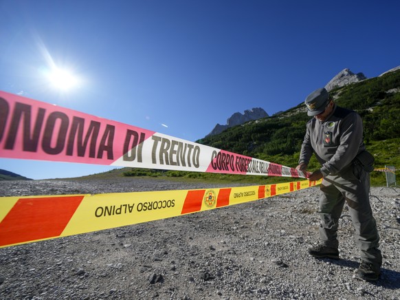 An Italian Financial police officer blocks the access to the Marmolada mountain and the Punta Rocca glacier near Canazei, in the Italian Alps in northern Italy, Wednesday, July 6, 2022, where an avala ...