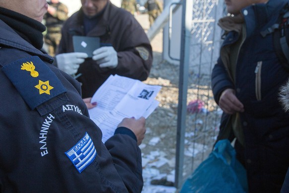 Griechische Polizisten kontrollieren Papiere von Flüchtlingen.<br data-editable="remove">