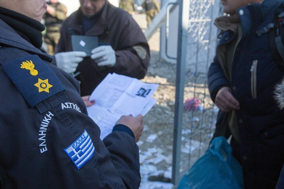 Griechische Polizisten kontrollieren Papiere von Flüchtlingen.